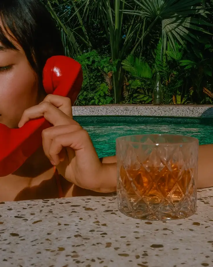 Bartender pouring a spirit into a glass with ice cubes
